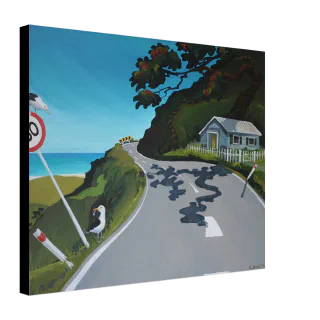 Angled view of a canvas print showing a winding coastal road, blue sea, cottage, tree, road sign, and two birds.