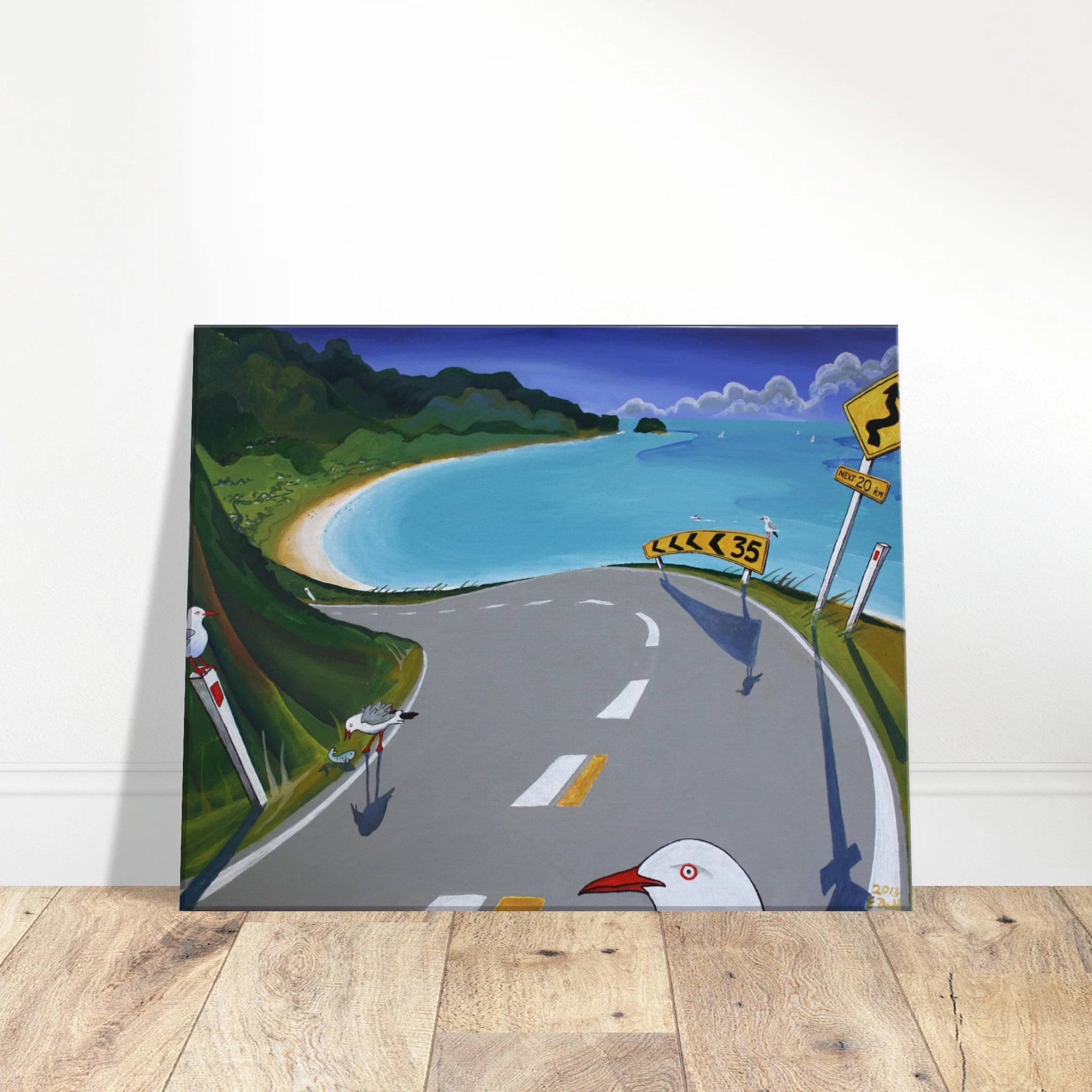 Canvas print featuring a coastal road, turquoise bay, green hills, sandy beach, road signs, and seagulls.