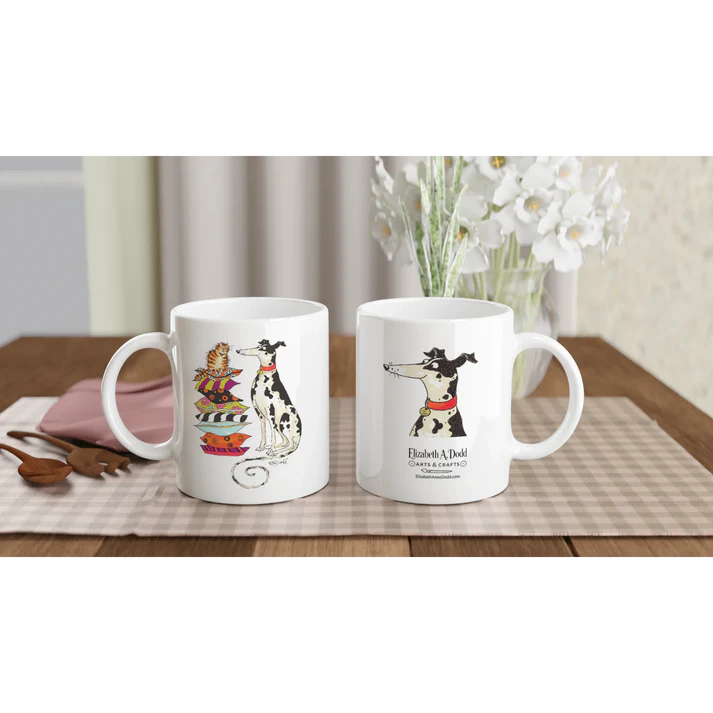 Two white mugs on a table, one with cat and spotted dog illustration and one with dog illustration and logo