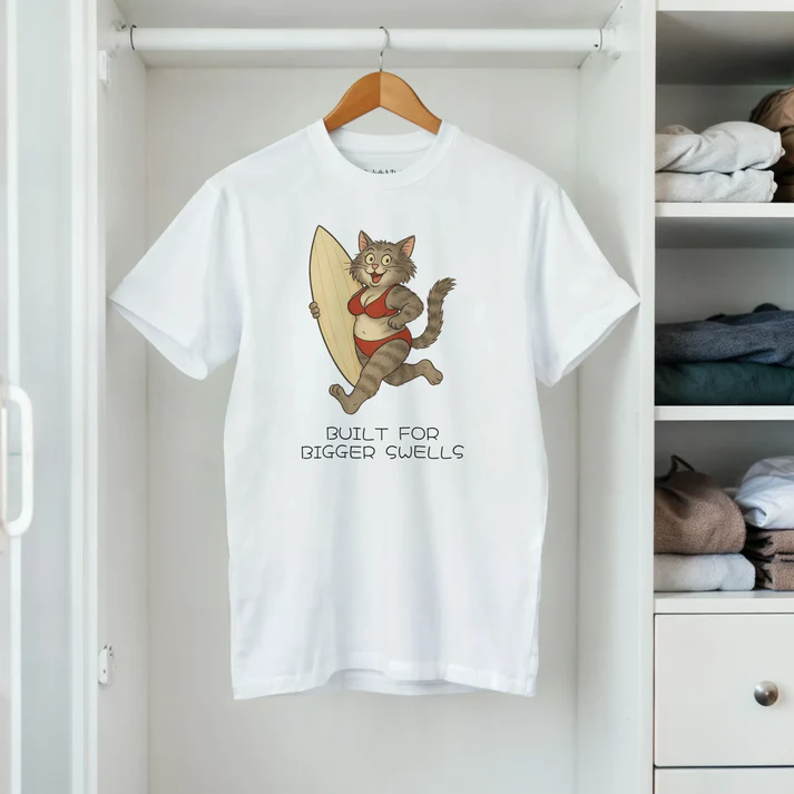 White T-shirt hanging in a wardrobe with a surfing cat illustration and Built for Bigger Swells text