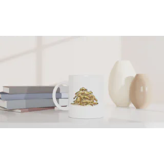 White mug with a pile of cats illustration on a tabletop beside books and vases