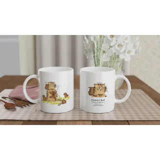 Two white ceramic mugs showing orange cat artwork and back logo on a table with flowers