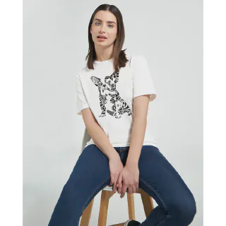 Woman sitting on a stool wearing a white t-shirt with French bulldog illustration and blue jeans