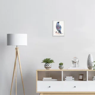Small white framed kokako print above a sideboard beside a floor lamp